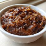 Close-up of deeply caramelized onions, the base for caramelized onion dip, glistening in a small white bowl.