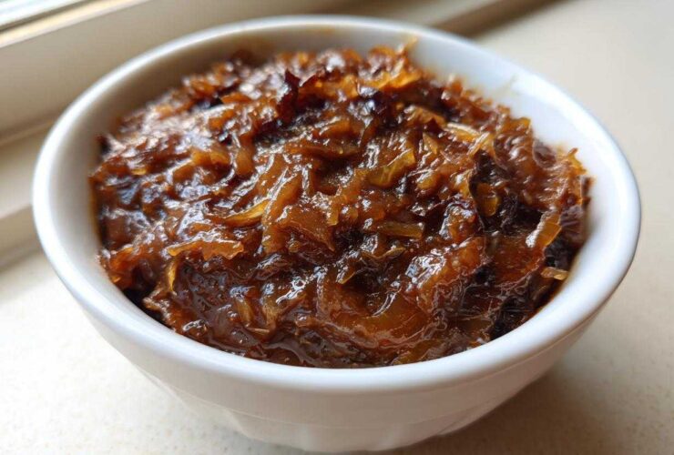 Close-up of deeply caramelized onions, the base for caramelized onion dip, glistening in a small white bowl.