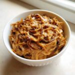 Close-up of creamy, rich caramelized onion dip topped with crispy fried onions in a white bowl.