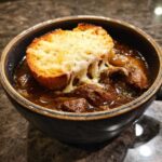 Close-up of rich french onion beef stew topped with a cheesy crouton.