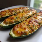 Three baked Cheesy Zucchini Boats filled with a creamy mixture and topped with melted, browned cheese and parsley.