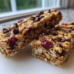 Close-up of two chewy no bake granola bars studded with chocolate chips and dried cranberries.
