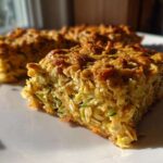 A close-up, sunlit view of a thick slice of Chewy Zucchini Oatmeal Bars showing texture and shredded zucchini.