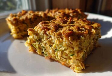 A close-up, sunlit view of a thick slice of Chewy Zucchini Oatmeal Bars showing texture and shredded zucchini.