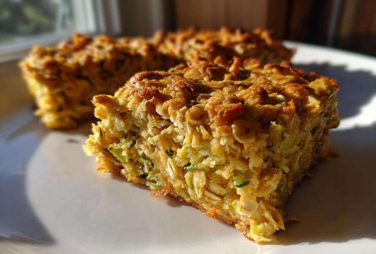 A close-up, sunlit view of a thick slice of Chewy Zucchini Oatmeal Bars showing texture and shredded zucchini.