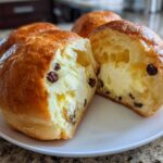 Close-up of chocolate chip vanilla custard brioches, one cut in half revealing rich vanilla custard filling.