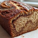 A close-up of a freshly baked cinnamon swirl banana bread loaf showing the moist crumb and cinnamon swirl inside.