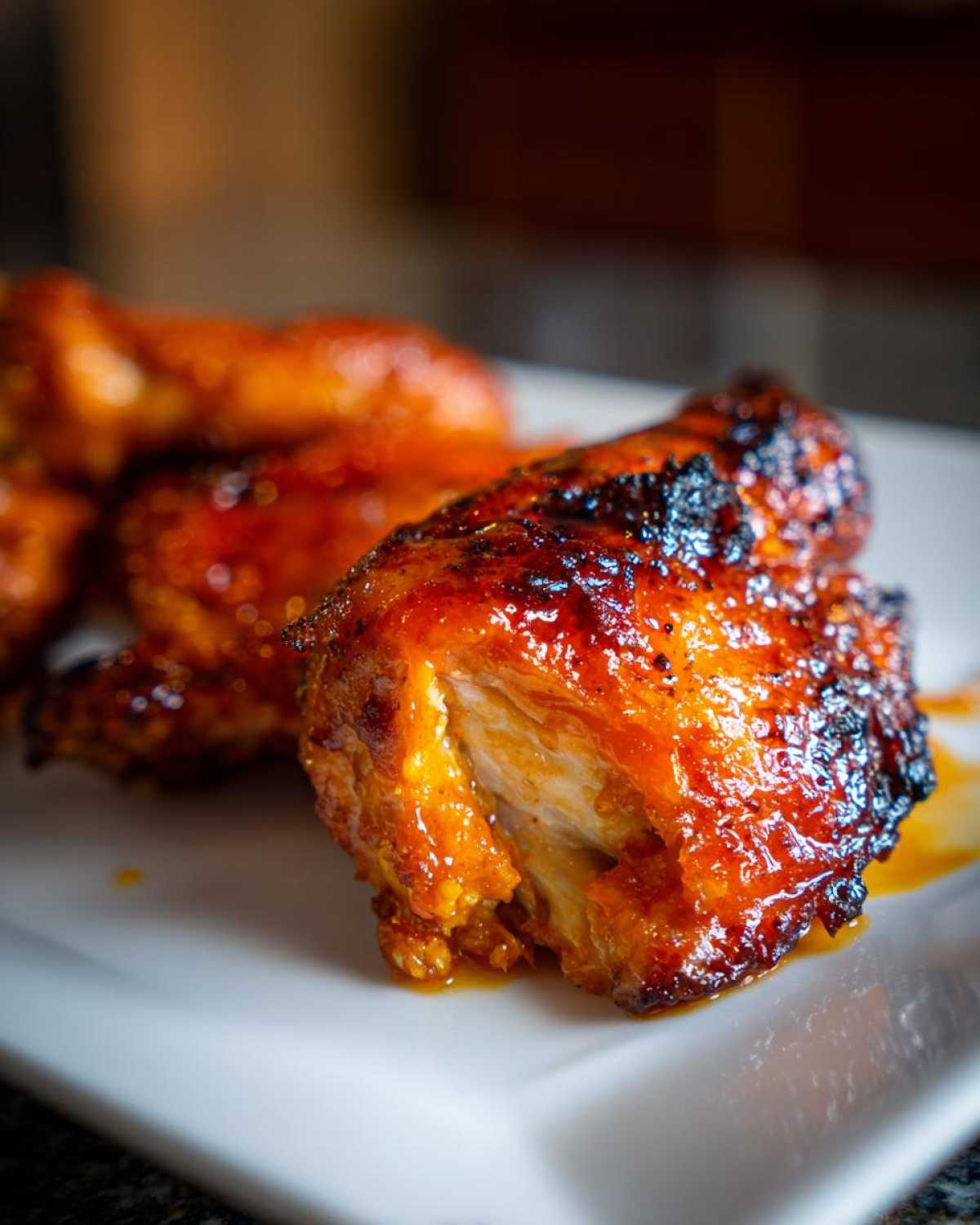 Close-up of a piece of hot honey chicken showing a crispy, dark glaze and juicy white meat inside.