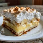 A close-up of a generous slice of creamy banana pudding made for dessert, featuring layers of vanilla pudding, bananas, wafers, and toasted meringue.