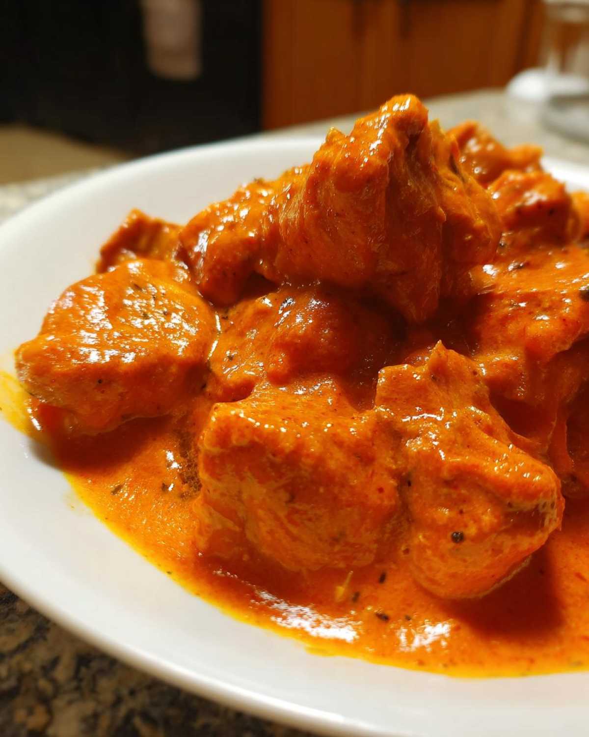 A close-up shot of tender chicken pieces coated in rich, orange-red sauce, showcasing the delicious butter chicken.