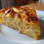 A perfect slice of creamy cheesy scalloped potatoes with a golden brown, bubbly top served on a white plate.