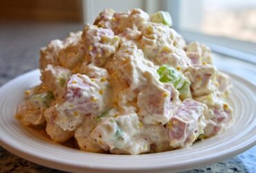 Close-up of a generous mound of creamy ham salad with diced ham and celery, served on a white plate.