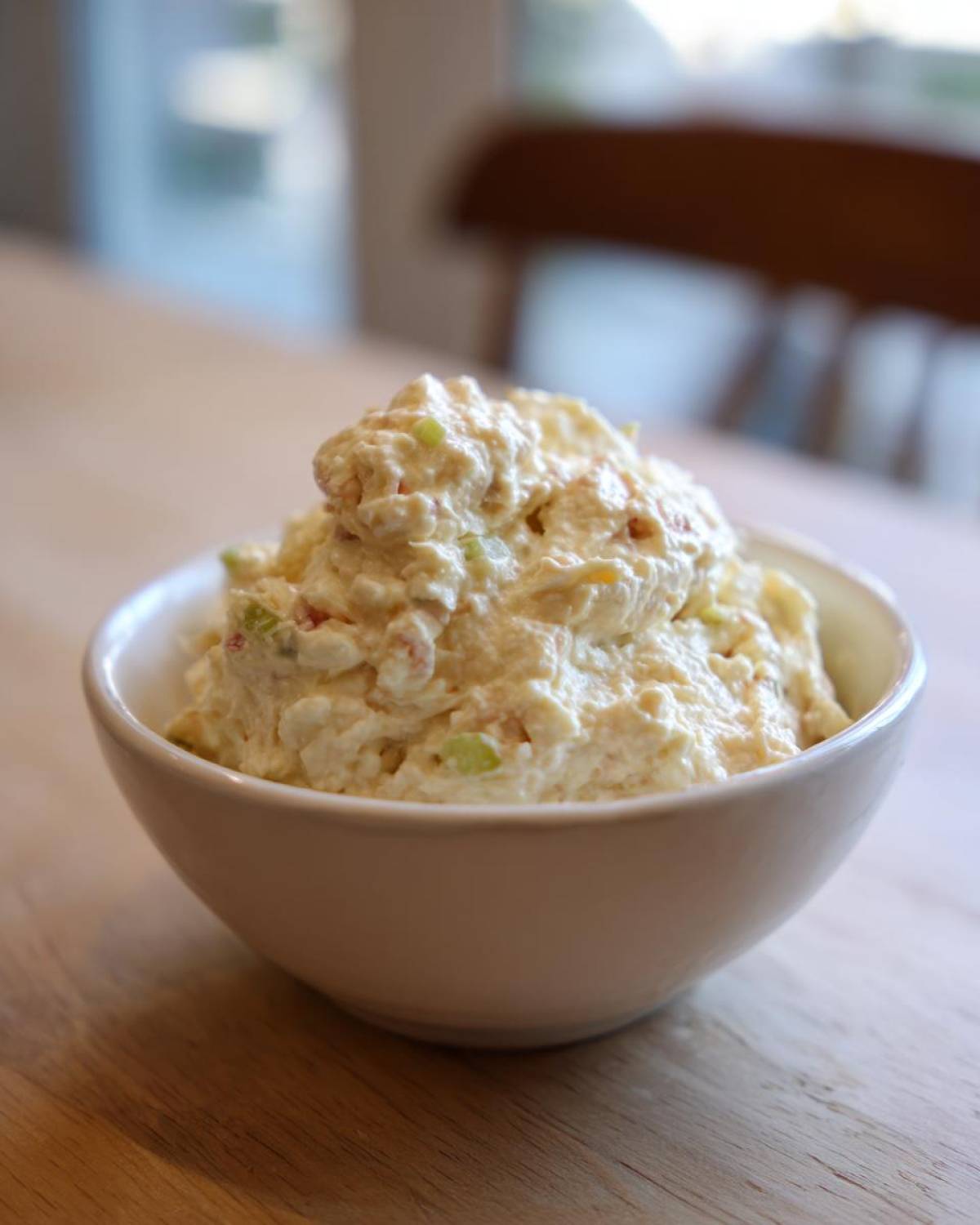 A generous scoop of creamy tuna dip with visible celery pieces served in a small white bowl.