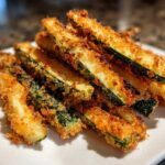 A close-up of a delicious stack of crispy zucchini fries, golden brown and perfectly seasoned.