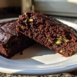 Two slices of moist Crowd Favorite Chocolate Zucchini Sheet Cake showing visible green zucchini shreds in the rich chocolate crumb.