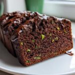 Close-up of a moist slice of Decadent Double Chocolate Zucchini Bread topped with chocolate glaze.