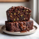 Two stacked slices of Decadent Double Chocolate Zucchini Bread drizzled heavily with melted chocolate ganache.