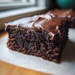 A moist, dark chocolate square of Decadent Frosted Zucchini Brownies topped with thick chocolate frosting.