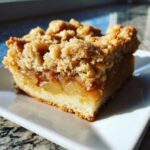 A close-up of one square of delicious & easy apple pie bars showing the thick apple filling and crumb topping.