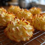 Close-up of golden brown, piped Duchess potatoes cooling on a wire rack after baking.