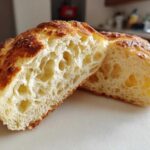 Close-up of a perfectly cooked english muffin cut in half, showing its signature open, airy crumb structure.