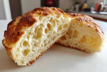 Close-up of a perfectly cooked english muffin cut in half, showing its signature open, airy crumb structure.