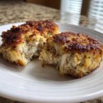 Two perfectly seared maryland crab cakes cut open to show the flaky white crab meat inside.