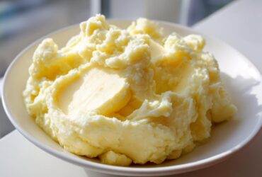 A close-up of creamy, fluffy mashed potatoes served in a white bowl, highlighting the smooth texture.