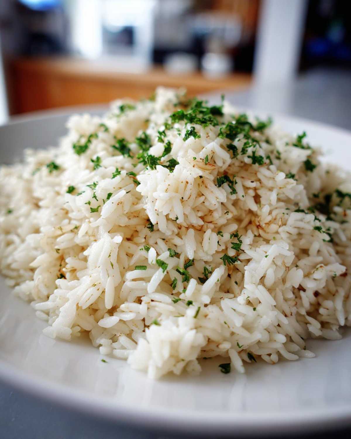 Close-up of a mound of fluffy white rice pilaf garnished generously with chopped green parsley.