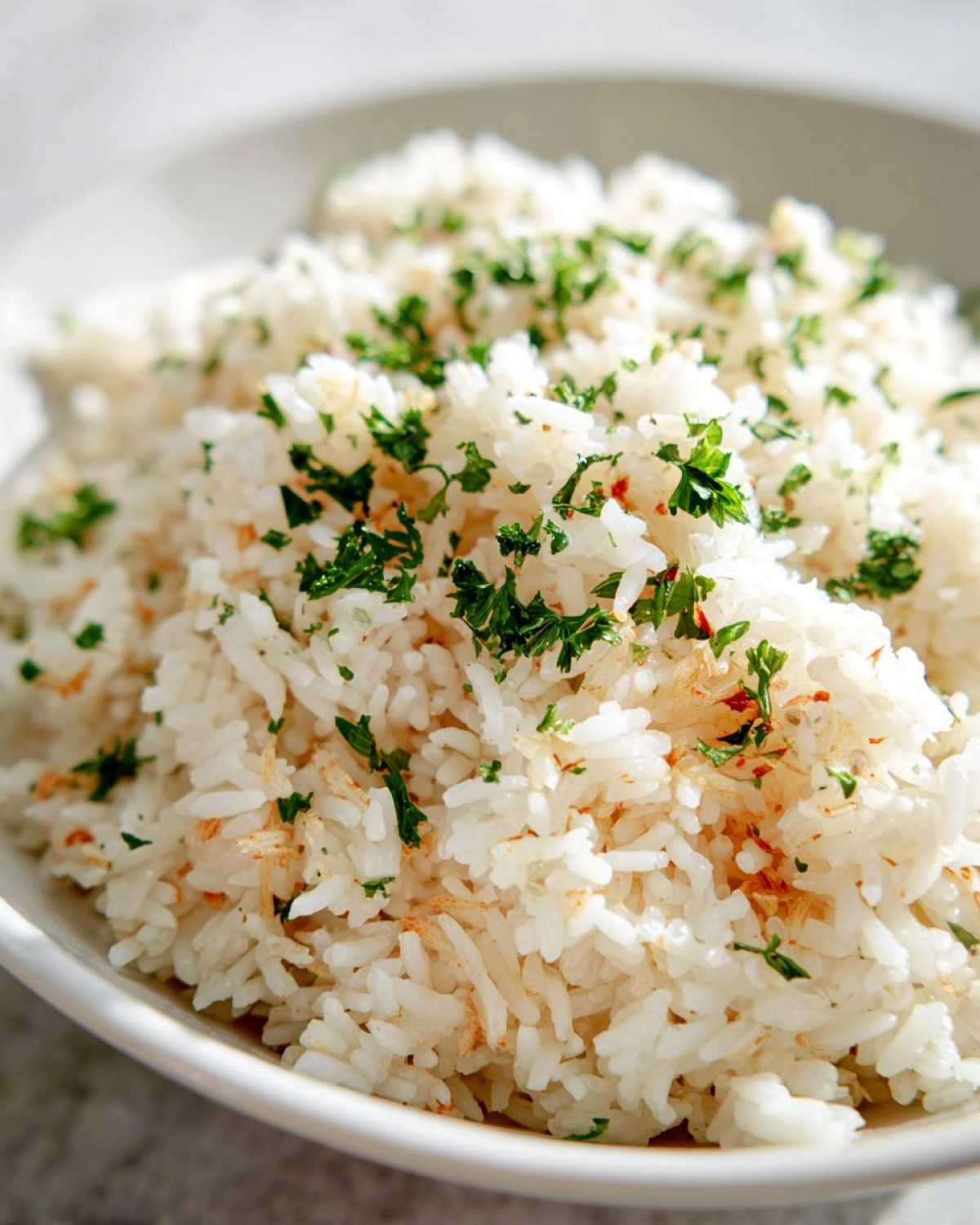 Close-up of fluffy white rice pilaf garnished with fresh chopped parsley and light seasoning.