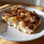 A close-up of a serving of amazing french onion chicken topped with melted cheese and caramelized onions.