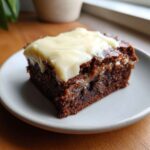 Close-up of a rich, fudgy banana bread brownies square topped with thick, creamy white frosting.
