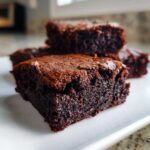 Close-up of a rich, fudgy slice of greek yogurt brownies showing a shiny, crackled top.