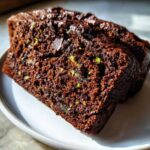 Two moist slices of dark brown Healthy Chocolate Zucchini Bread showing flecks of green zucchini.