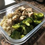 Close-up of a healthy meal prep container with seasoned chicken, quinoa, and steamed broccoli, illustrating how you’re eating healthy wrong for busy.