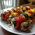 Close-up of colorful grilled vegetable skewers featuring zucchini, peppers, and mushrooms, heavily seasoned with herbs.