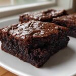 A close-up of a rich, fudgy square of homemade 4 ingredient cottage cheese brownies on a white plate.