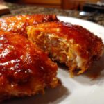 Close-up of crispy hot honey chicken cut open, showing juicy white meat inside the sticky, sweet glaze.