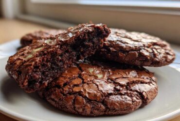Close-up of fudgy brownie cookies, one broken in half to show the rich interior texture.