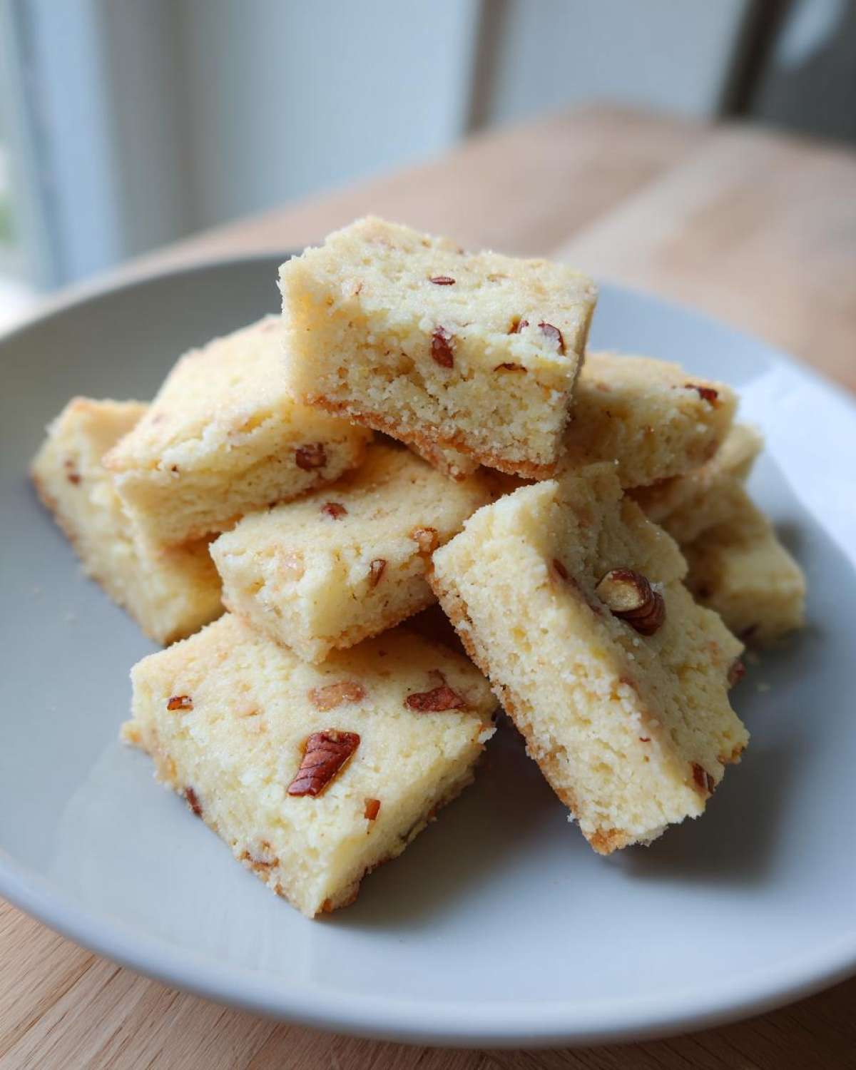A stack of freshly baked Maple Pecan Shortbread Cookies cut into squares, showing visible pecan pieces.