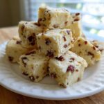 Close-up of several square Maple Pecan Shortbread Cookies stacked on a white plate.