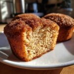 A close-up view showing the crumb texture of a halved Mini Apple Cider Donut Muffin coated in cinnamon sugar.