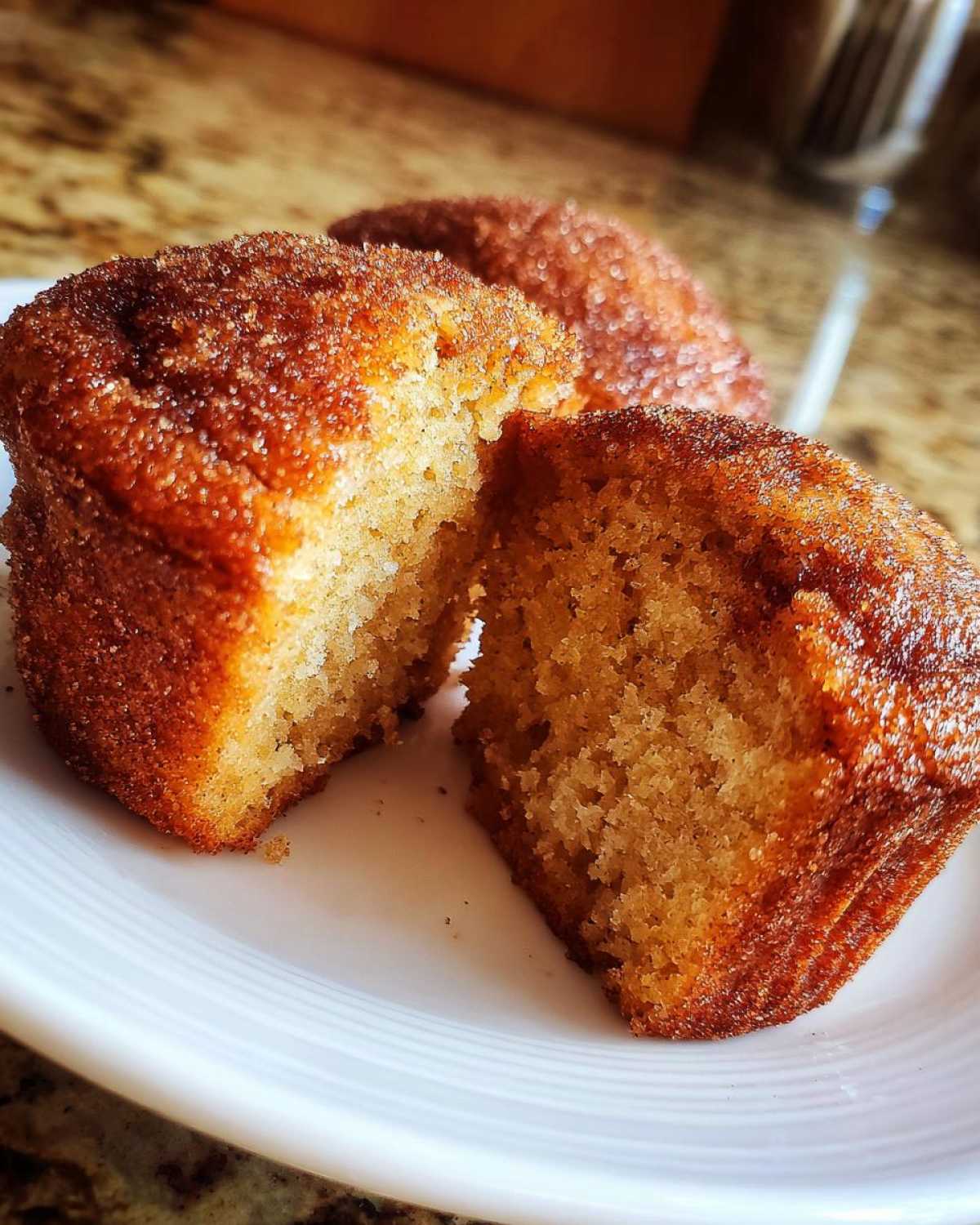 Close-up of a Mini Apple Cider Donut Muffin cut in half showing the moist interior and cinnamon sugar coating.