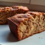 Close-up of two slices of moist apple cinnamon cake showing tender crumb and chunks of baked apple.