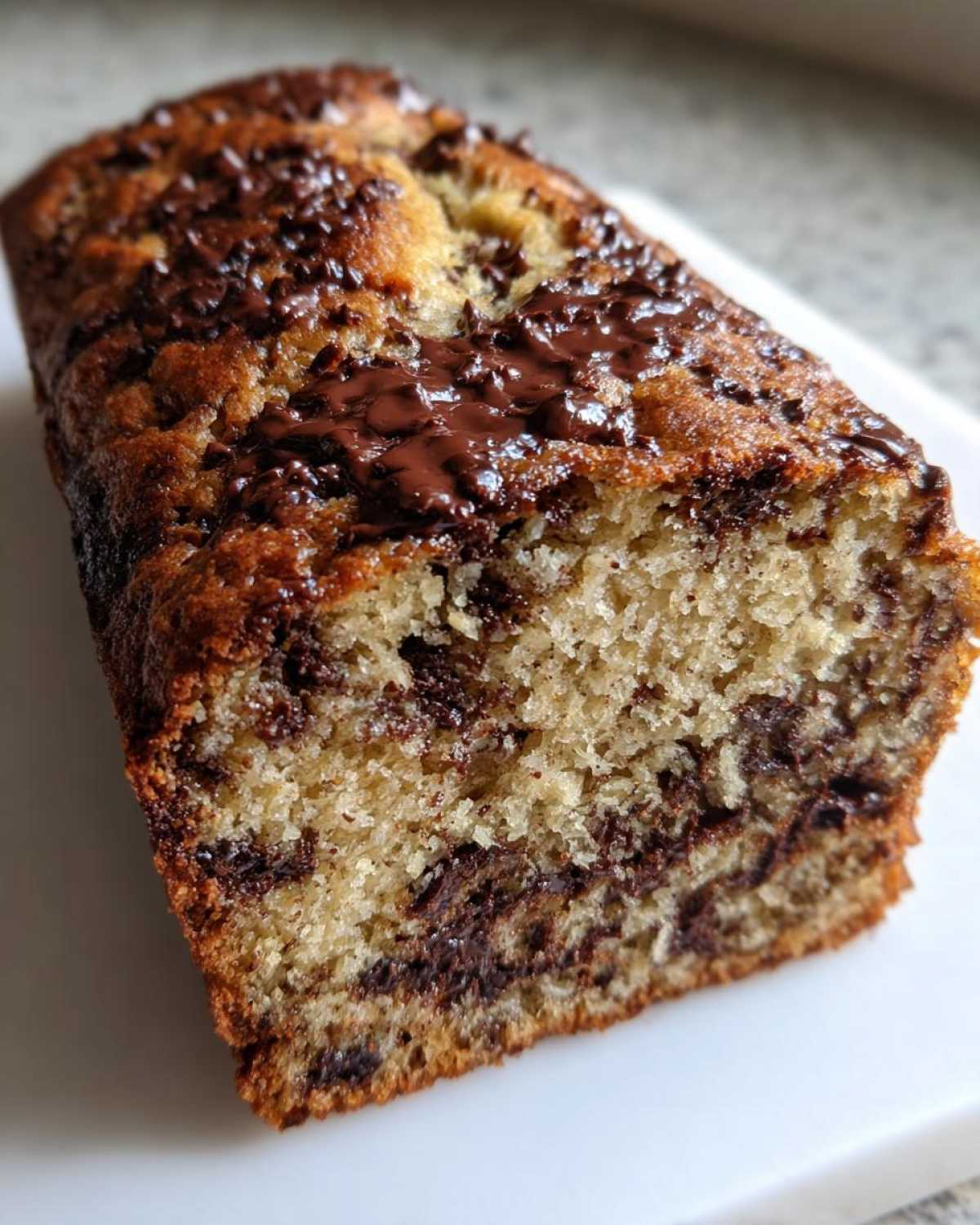 Close-up of a freshly baked chocolate chip banana bread loaf showing a moist crumb and melted chocolate chips on top.