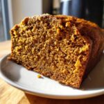 Close-up of a thick slice of moist easy pumpkin bread showing its rich orange-brown crumb texture.