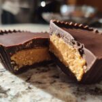 Close-up of homemade peanut butter cups cut in half showing the thick peanut butter filling and chocolate shell.