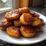 Close-up of perfectly caramelized pan fried cinnamon apples stacked on a white plate.