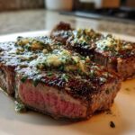 Two perfectly seared tuna steak portions, cooked medium-rare, topped with glistening garlic herb butter.