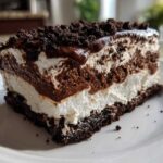 Close-up of a slice of quick & easy decadent dessert with layers of chocolate mousse, white cream, and a dark cookie crust.